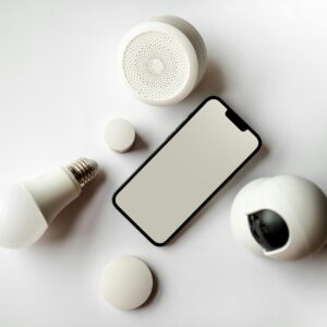Home Flat lay of smartphone and smart home devices on a white backdrop, showcasing modern technology.